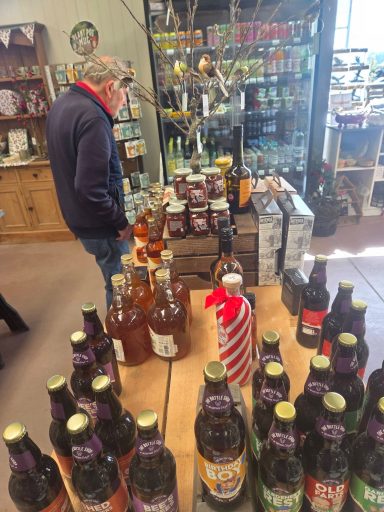 A man examines shelves filled with various bottled beverages in a store.